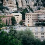 white concrete building near green trees and mountain during daytime