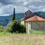 brown and white concrete house near green trees and mountain during daytime